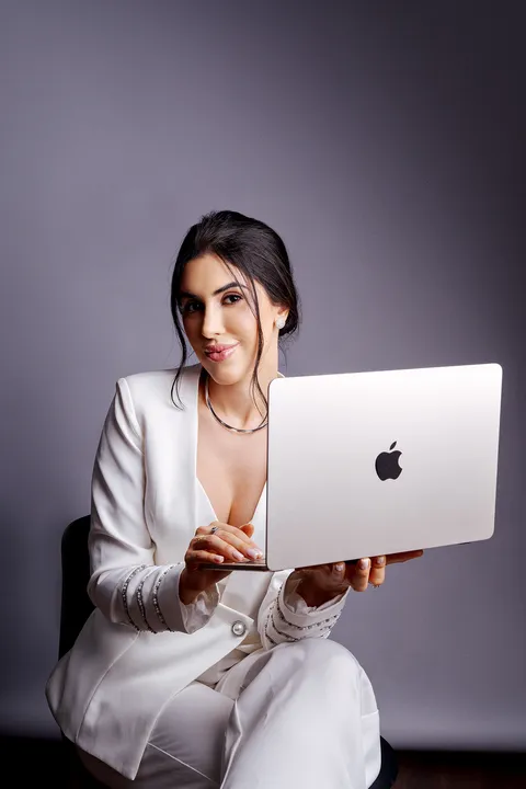 Profissional segurando notebook, retrato corporativo em fundo cinza