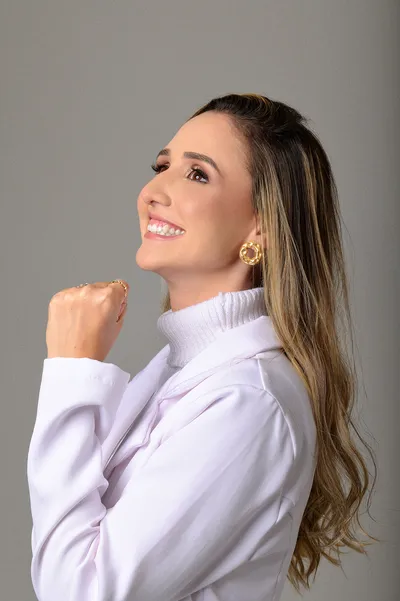 Profissional sorrindo em retrato de perfil, fundo neutro claro